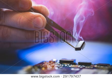 Man holding smoking chip over the computer CPU board. IT technology, fixing electronical devices.
