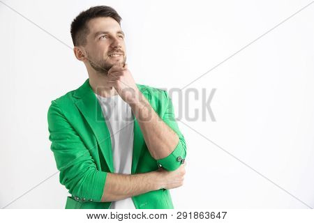 Looking For The Best Moment. Young Dreaming Smiling Man Is Waiting For Chanses Isolated On Gray Back