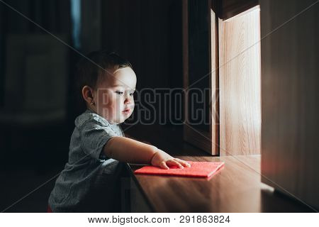 A Little Girl With A Rag Wiping The Dust From The Cabinet