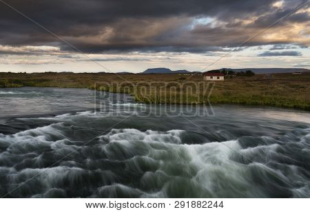 Typical Rural Icelandic House At River Coastline. Horizontal Shot At The Sunset
