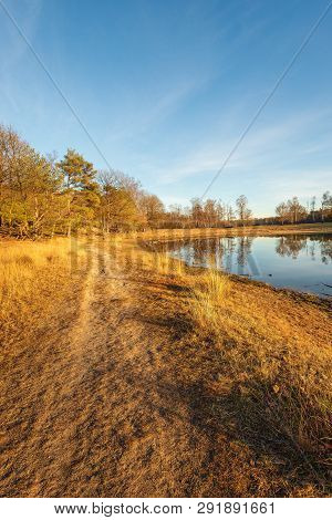Vertical Image Of A Small Lake In The Low Light Of The Setting Sun. The Photo Was Taken In The Dutch
