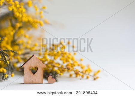Closeup Wooden House With Hole In Form Of Heart With Yellow Mimosa Branches On Lilac Background With