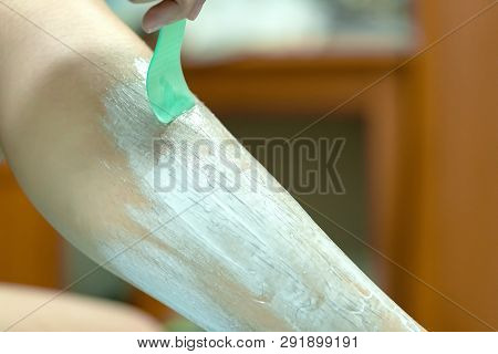 Woman Epilating Leg With Depilation Cream And Spatula. Scrubs Hair Removal Cream