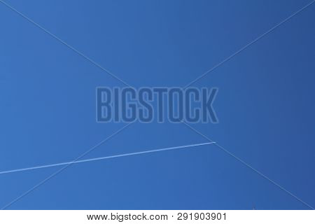 Bright Blue Sky On Which The Plane Flies Leaving A Trail.