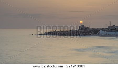 Nerja, Malaga, Andalusi, Spain - February 19, 2019: Long Exposure Of The Sun Over The Ruins Of A Tow