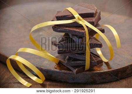 Pyramid Of The Dark Chocolate Tied With Yellow Ribbon On The Bruwn Wooden Plate