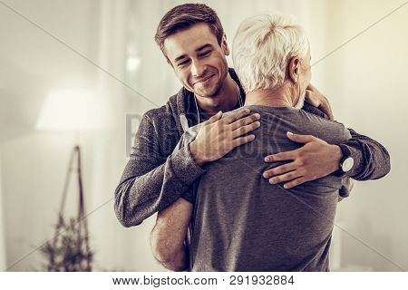 Smiling Handsome Young Man Embracing Grey-haired Dad Cheering Him Up
