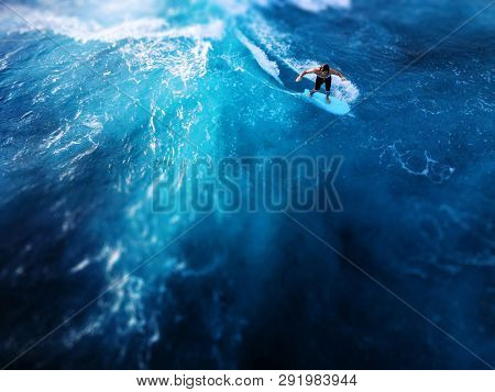 OAHU / USA - 15 NOVEMBER 2018: Surfer rides the ocean tropical wave. Aerial view of Makaha surf spot, west coast of Oahu, Hawaii. Tilt shift effect applied