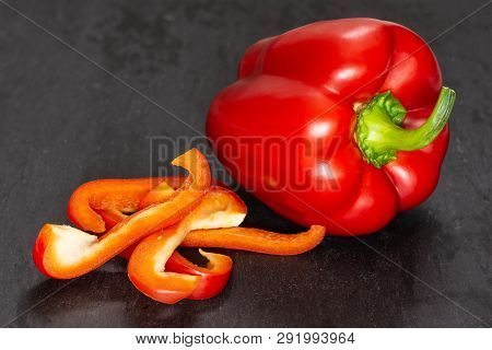 Group Of One Whole Four Slices Of Bulgarian Red Bell Pepper On Grey Stone