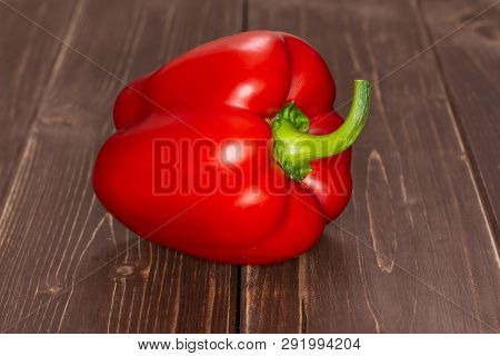 One Whole Bulgarian Red Bell Pepper On Brown Wood