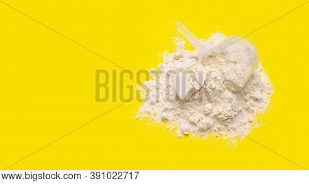 Heap Of Protein Powder With Plastic Spoon On Yellow Background