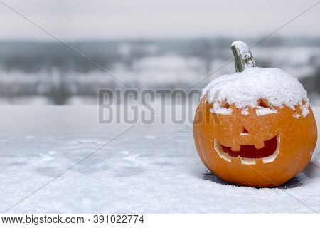 A Jack-o'-lantern Carved Pumpkin During A Snow Fall During The Fall. Concept: Cold Halloween. Snow F