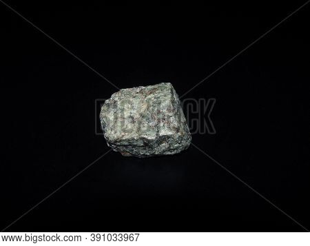 A Sample Of The Urtite Rock Is Gray-green On A Black Background