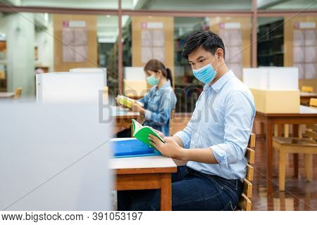 Two Asian University Students Wearing Face Mask And Sitting In Library Social Distance From Other 6 