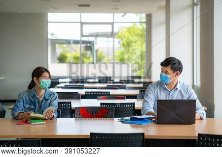 Two Asian University Students Wearing Face Mask And Sitting In Library Social Distance From Other 6 