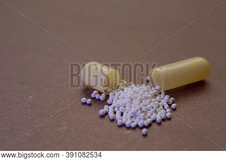 The Opened Pill Is Yellow, With White Balls Inside.
