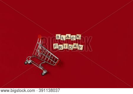 Black Friday Phrase Made Of Wooden Blocks And Shopping Cart Flat Lay On Red Background Top View. Aut