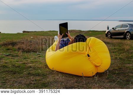 Pretty Young Asian Woman Sitting On A Yellow Lamzak Having A Video Chatting With Tablet On A Cliff N