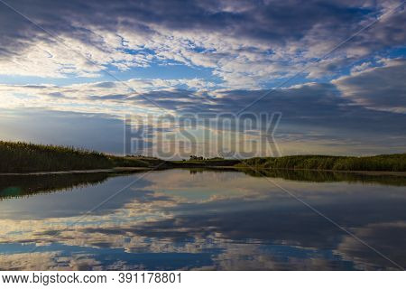 Silvery Sunrise Over A Quiet Lake.  Silver Clouds  Are Mirrored  Reflected In The Water Surface. Nat
