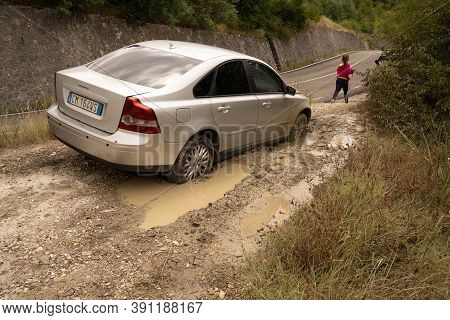 Abruzzo, Italy - July 18, 2020, Silver Car And A Person Stuck Deep In Mud In Abruzzo, Italy