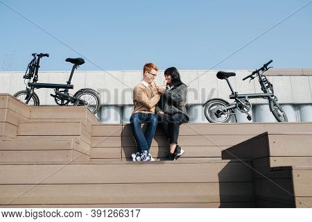 Happy Couple Sitting On The Stairs Outdoors, Eating Ice Cream