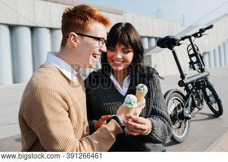 Laighing Man An Woman Sitting Outdoors, Holding Ice Cream, Talking, Laughing