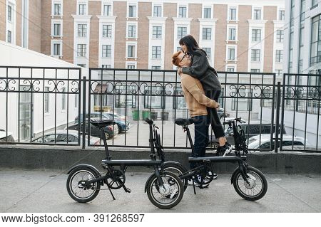 Happy Young Man Holding His Girl In The Air By Her Thighs. Side View