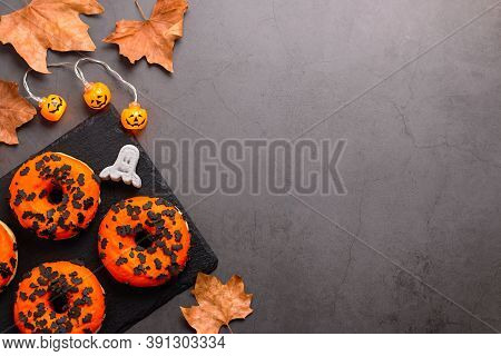 Pumpkin And Chocolate Donuts, Spooky Ghosts Marshmallows And Dried Leaves On Grey Stone Table Top - 