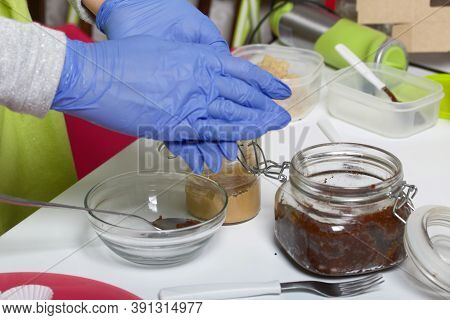 A Woman In Rubber Gloves Makes Candies From Dried Fruits And Nuts At Home In Self-isolation During A