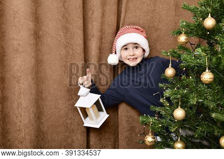 The Boy In Santa Cap, Delighted And Pleasantly Surprised, Half Behind The Christmas Tree.