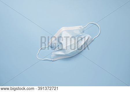 Disposable Ear-loop Face Mask On Blue Background. Respiratory Virus And Bacteria Protection Concept.