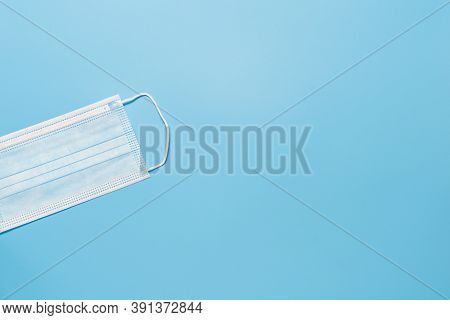 Surgical Ear-loop Mask On Blue Background With Copy Space. Respiratory Virus And Bacteria Protection