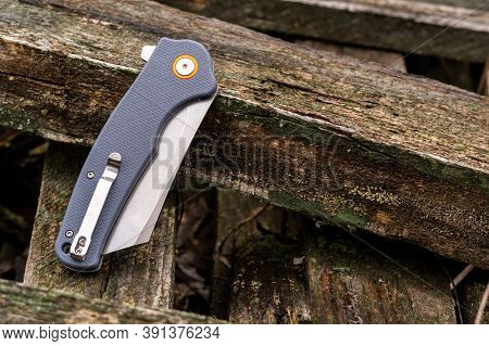 The Reverse Side Of The Knife Has A Clip For Carrying. Knife On Wooden Rural Boards. Top.
