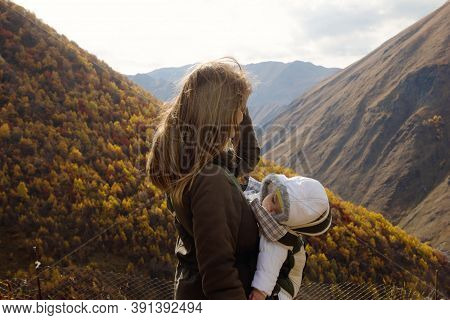 Portrait Of Young Beautiful Woman With Her Little Sleeping Daughter In Ergo Carrier On A Background 
