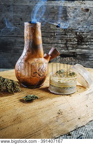 Old Brown Steamung Bong And Open Cannabis Grinder With Chopped Marijuana Weed And Medical Cannabis I