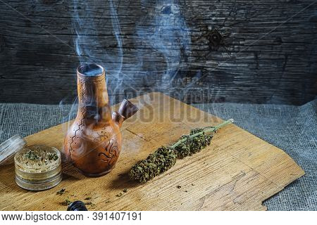 Old Brown Steamung Bong And Open Cannabis Grinder With Chopped Marijuana Weed And Medical Cannabis I