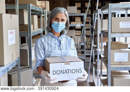 Mature Female Warehouse Worker Volunteer Wearing Face Mask Standing In Shipping Storage Delivery Cha