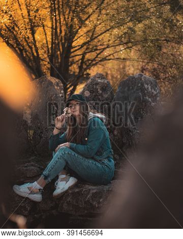 Portrait Of An Attractive Brunette Sitting In A Stone Well At The Rajcica Wells Landmark. Wearing Je