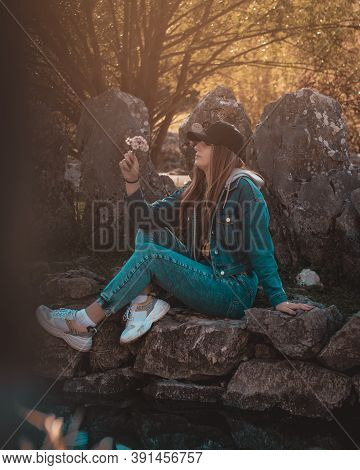 Portrait Of An Attractive Brunette Sitting In A Stone Well At The Rajcica Wells Landmark. Wearing Je