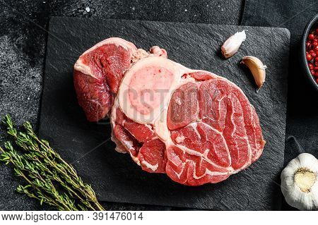 Osso Buco Meat. Raw Cross Cut Veal Shank And Seasonings For Cooking Osso Buco. Black Background. Top