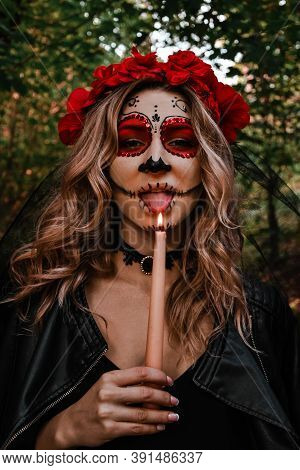 Happy Halloween Concept. Scared Horrible Female In Special Outfit, Wears White Clay Skull, Professio