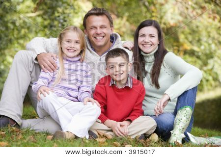 Familie sidder på græs omgivet af blade