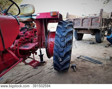 Red Tractor Lifted Up On Iron Chassis Jack And Punctured Tyre Opened For Repair