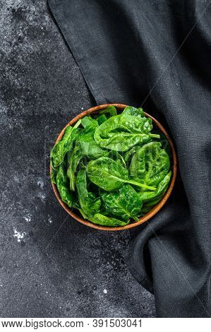 Young Raw Spinach In A Wooden Bowl. Black Background. Top View