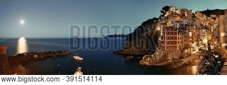 Riomaggiore waterfront view with buildings and moonset in Cinque Terre at night panorama, Italy.