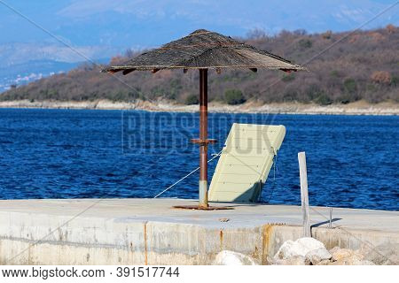 Wicker Beach Parasol With Rusted Wire On Top Mounted On Thick Metal Pole On Top Of Concrete Pier Nex