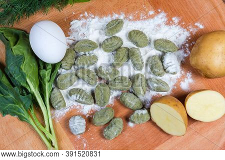 Uncooked Potato Gnocchi With Spinach In Flour, Several Ingredients On The Wooden Board, Top View