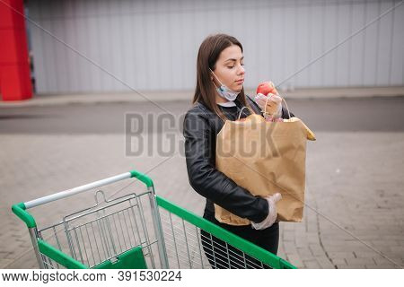 Groceries In Females Hand By The Car Truck. Woman In Protective Mask And Disposable Gloves. Fresh Fr