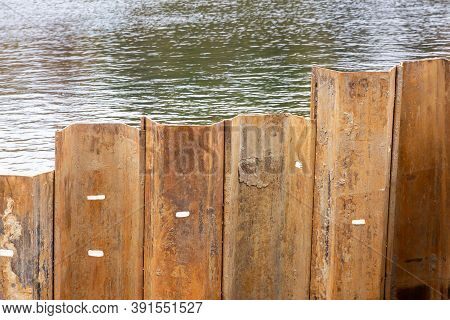 Larsen Sheet Piling At A Construction Site. Hammered Metal Piles On The River Bank