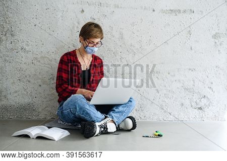 Young Student With Laptop Sitting On Floor Back At College Or University, Coronavirus Concept.